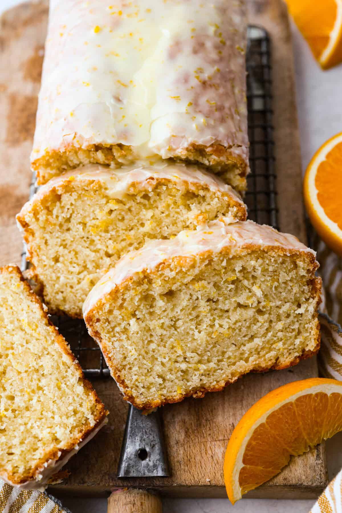 This glazed orange loaf is sunshine in every slice! Fresh orange zest and juice give it a bright citrus flavor. It's just like this incredibly popular Lemon Loaf. It’s the kind of quick bread you keep coming back to for just one more slice. Angle shot of the baked and glazed bread on a cutting board with slices cut out of it.