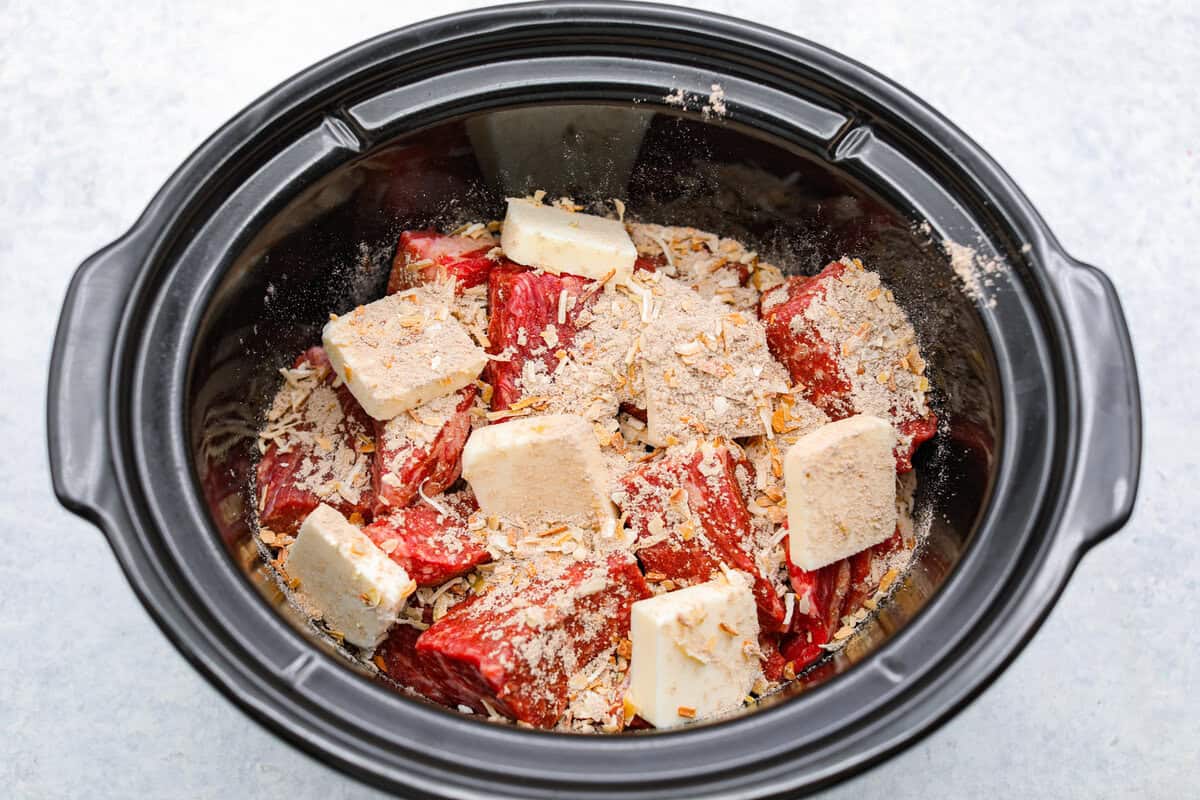 Cook the roast low and slow until tender, j The onion and butter soup mixture is added to the meat in the slow cooker.