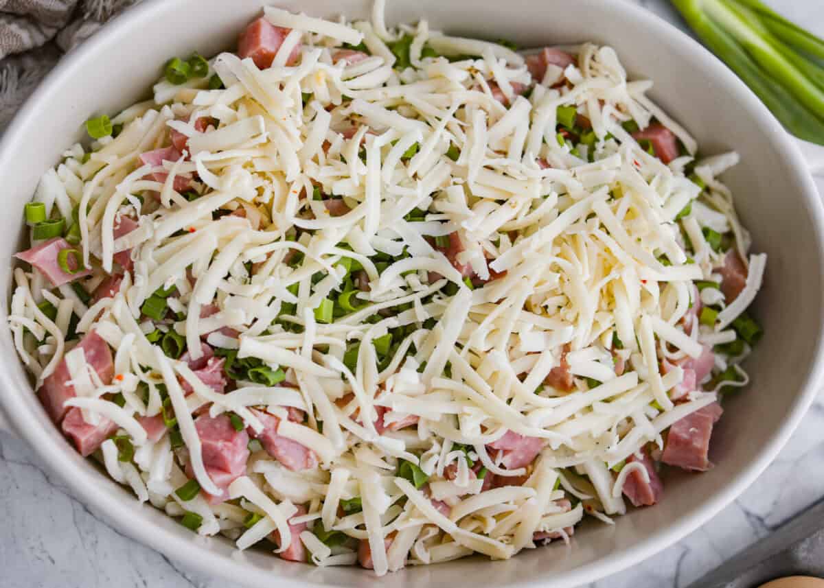 This farmer's casserole is my answer to summer mornings when the kids want cereal again, but I want them to eat something that will actually keep them full. Itโs packed with protein, and it's easy to customize with fresh garden veggies. Ham, green onions, and cheese added to the baking dish.