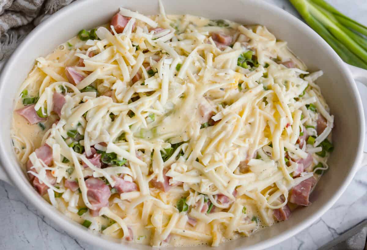 This farmer's casserole is my answer to summer mornings when the kids want cereal again, but I want them to eat something that will actually keep them full. Itโs packed with protein, and it's easy to customize with fresh garden veggies. Egg mixture dumped over the top of the assembled farmer's casserole.