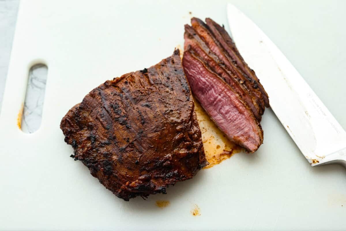 Grilled steak fajitas are one of those dinners that feels fun the second it hit the table. The steak is juicy and smoky, the peppers and onions are tender and flavorful, and everyone gets to build their fajitas just the way they like them. Someone slicing the cooked steak.