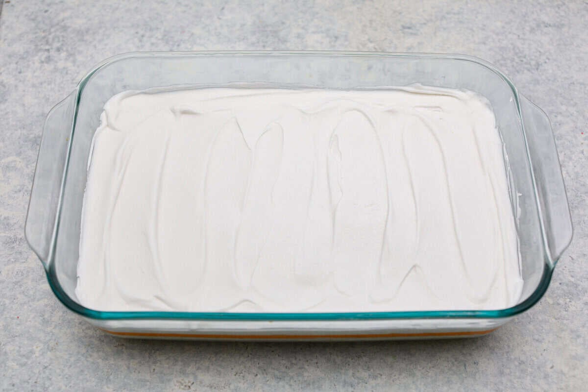 Orange creamsicle lush is sunshine in dessert form! With creamy orange layers, a buttery golden Oreo crust, and bright fresh citrus flavor, this easy no-bake dessert is a fun twist on my popular Lemon Lush that’s perfect for summer. Whipped topping layer on top of the orange layers.
