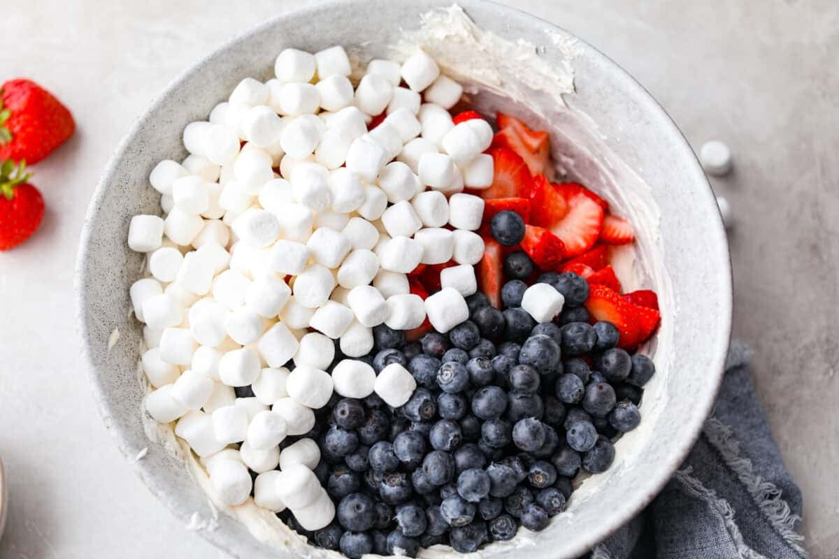 This red, white, and blue cheesecake salad is the fun summer side dish everyone goes back for. It’s creamy, fluffy, packed with berries and marshmallows, and so easy to bring to a BBQ, potluck, or Fourth of July party. Marshmallows, and berries added to the yogurt mixture.