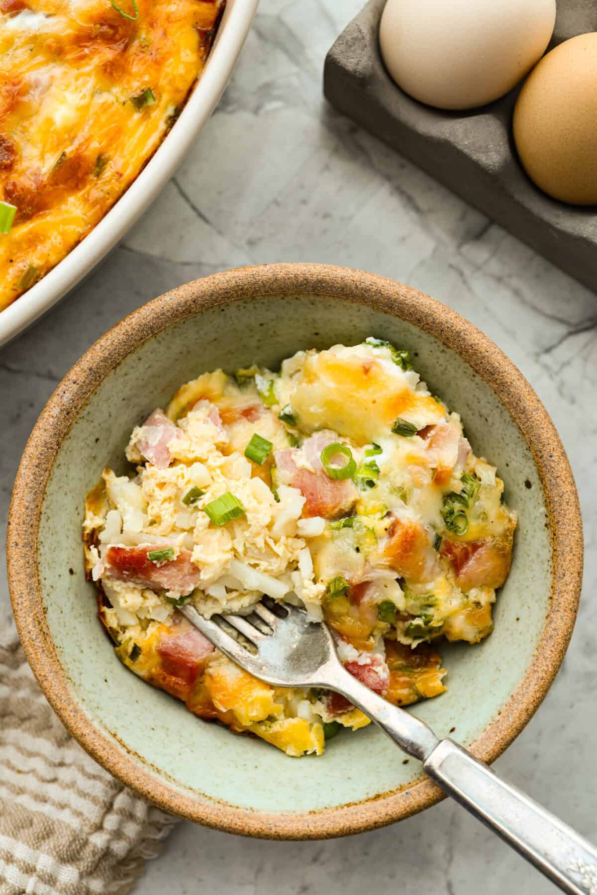 This farmer's casserole is my answer to summer mornings when the kids want cereal again, but I want them to eat something that will actually keep them full. Itโs packed with protein, and it's easy to customize with fresh garden veggies. Serving of farmer's casserole in a bowl with a fork.