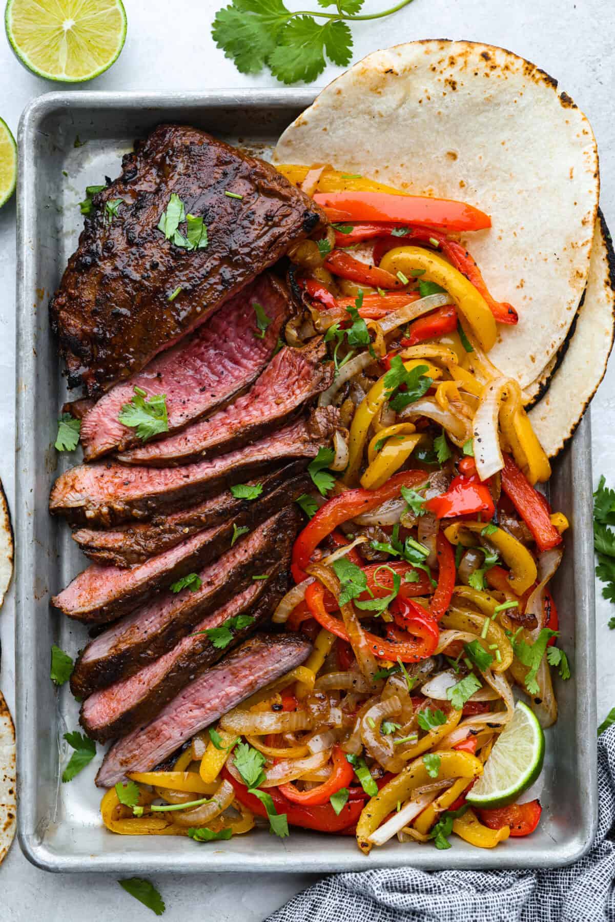 Grilled steak fajitas are one of those dinners that feels fun the second it hit the table. The steak is juicy and smoky, the peppers and onions are tender and flavorful, and everyone gets to build their fajitas just the way they like them. Sheet pan with grilled steak fajitas and veggies and tortillas.