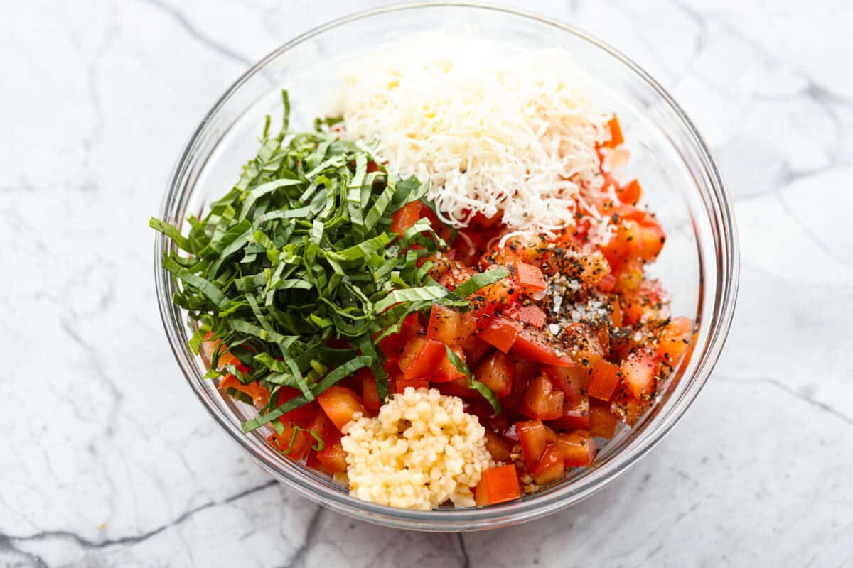 Iโve loved homegrown tomatoes since I was a kid, and this easy bruschetta recipe is one of my favorite ways to use them. The fresh basil, garlic, olive oil, and crispy toasted bread with that balsamic glaze make such a good flavor! All of the tomato topping ingredients added to a bowl.