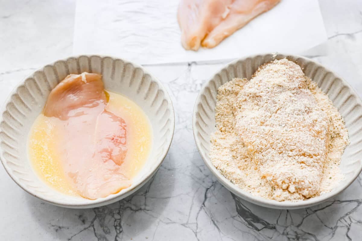 My family and I cannot get enough of this versatile summer vegetable! Whether you use it for a side dish or the entrรฉe, its tender texture and ability to absorb flavor is unmatched. Take advantage of zucchini being in season and try out some of my other favorite zucchini recipes! Chicken being dredged in egg wash and bread crumbs in separate bowls.