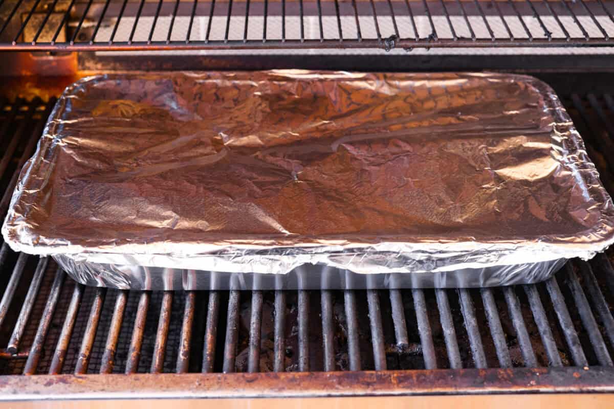 These grilled BBQ ribs are what summer cookouts are all about! Slow-cooked until fall-off-the-bone tender, then finished with a sticky, caramelized layer of BBQ sauce that'll have everyone licking their fingers. Ribs in a disposable aluminum pan covered and on the grill.