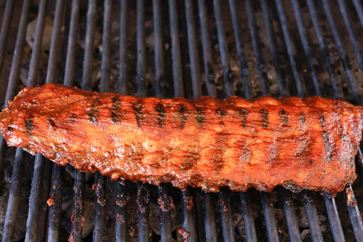 These grilled BBQ ribs are what summer cookouts are all about! Slow-cooked until fall-off-the-bone tender, then finished with a sticky, caramelized layer of BBQ sauce that'll have everyone licking their fingers. Grilled bbq ribs covered in bbq sauce.