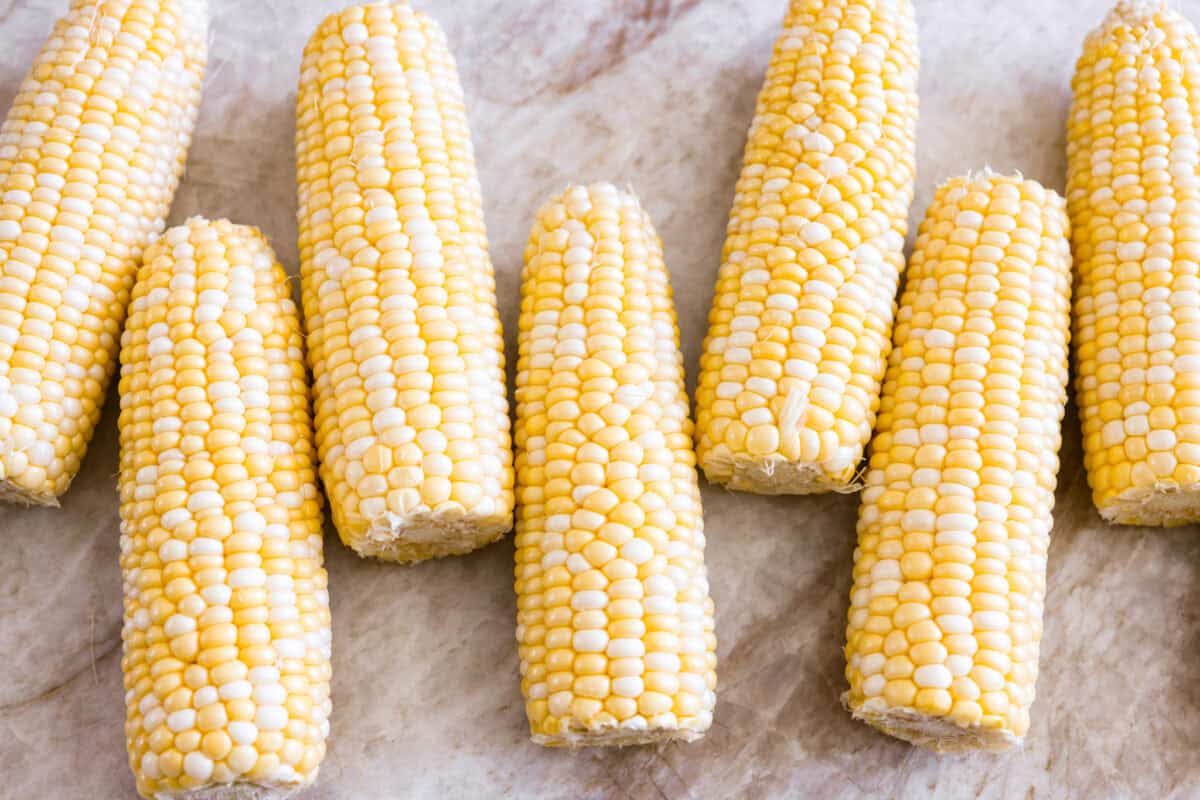 My crack corn on the cob takes summer corn to a whole new level! Smothered in a creamy ranch sauce and topped with bacon, cheddar, and green onions, it's the kind of side dish that disappears before the main course even hits the table. Corn cobs husked and ready to be cooked.