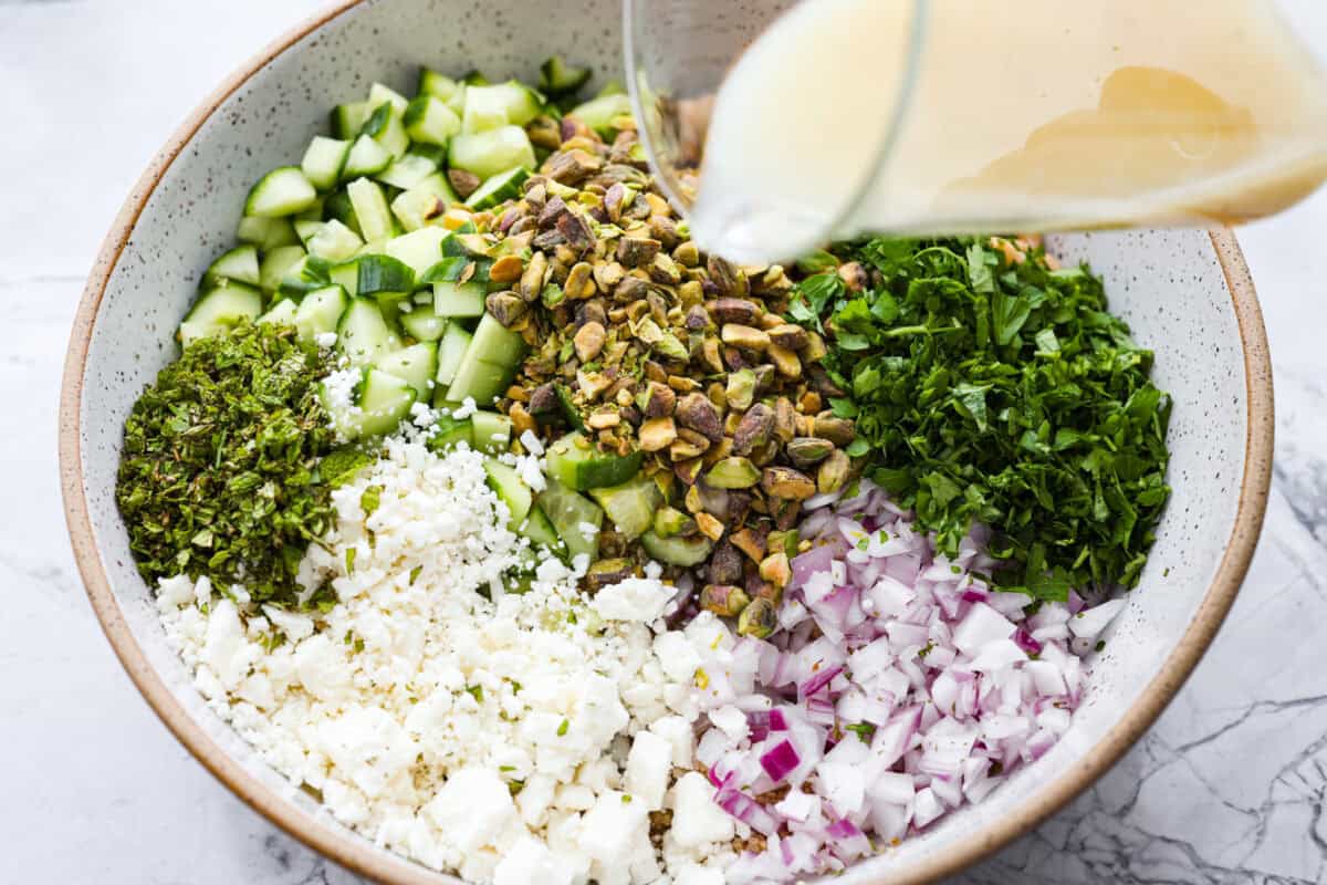 Someone pouring the dressing over the salad ingredients.