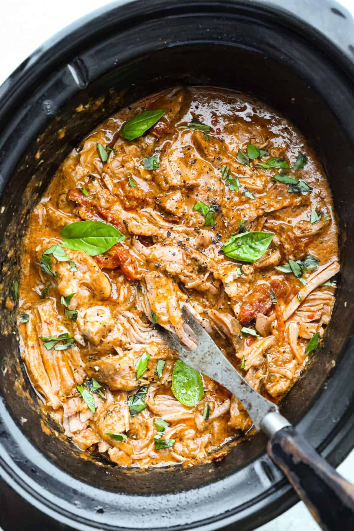 Marry Me Pork Roast lives up to its name! Tender pork, slow cooked in a creamy, garlicky sun-dried tomato sauce that's so good! Pile it over mashed potatoes or buttered noodles to soak up every drop. Top down shot of marry me pork roast in a slow cooker.