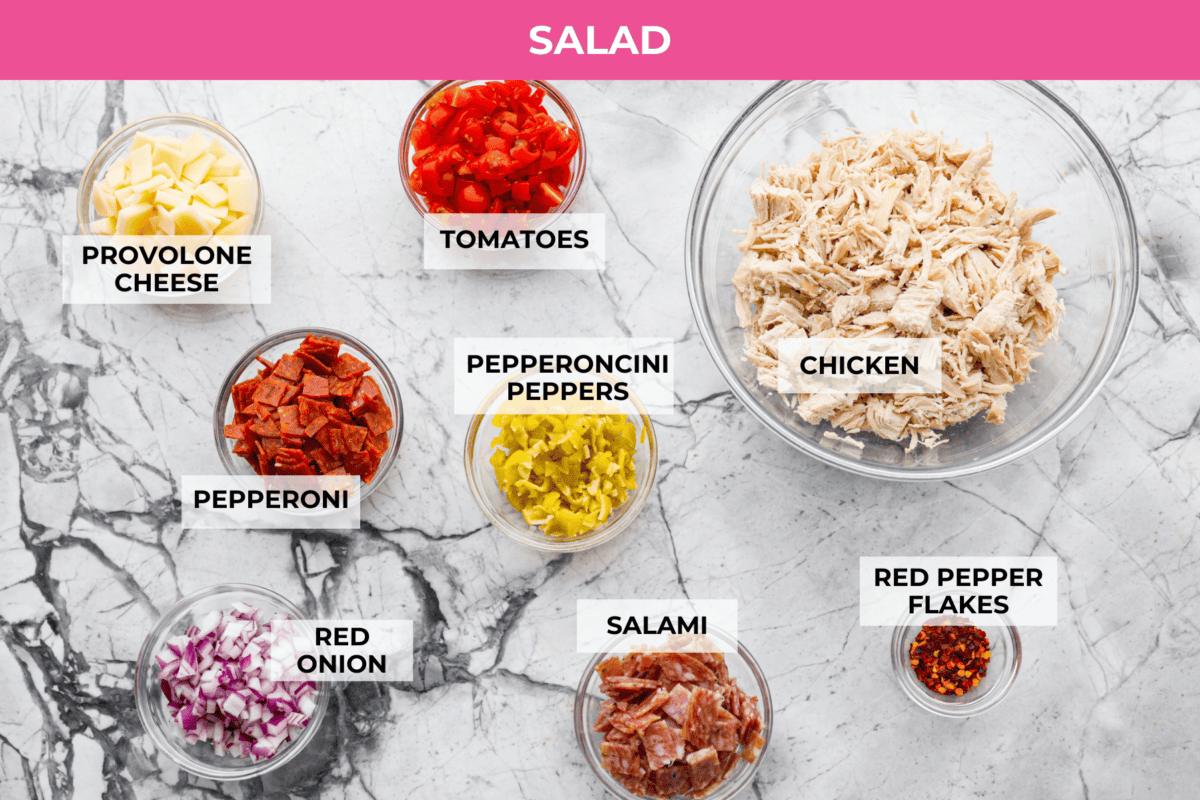I know you guys love my famous grinder sliders. This grinder chicken salad brings all those bold flavors into one easy recipe. It's hearty, creamy, and perfect for lettuce wraps or a quick lunch straight from the bowl. Overhead shot of labeled grinder chicken salad ingredients.