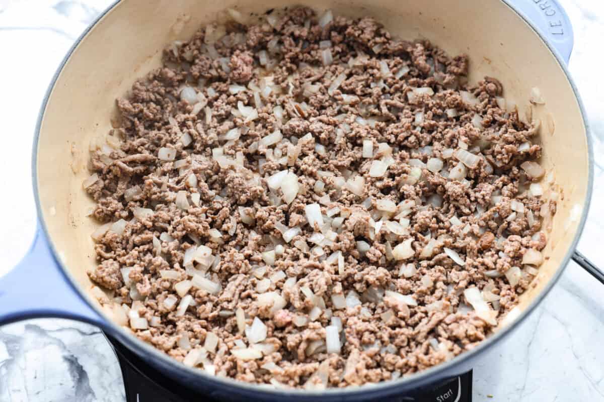 Brown beef and onions cooking in a skillet. 