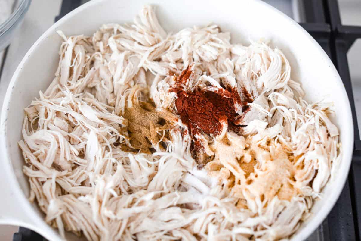 Shredded chicken and seasonings added to the skillet.
