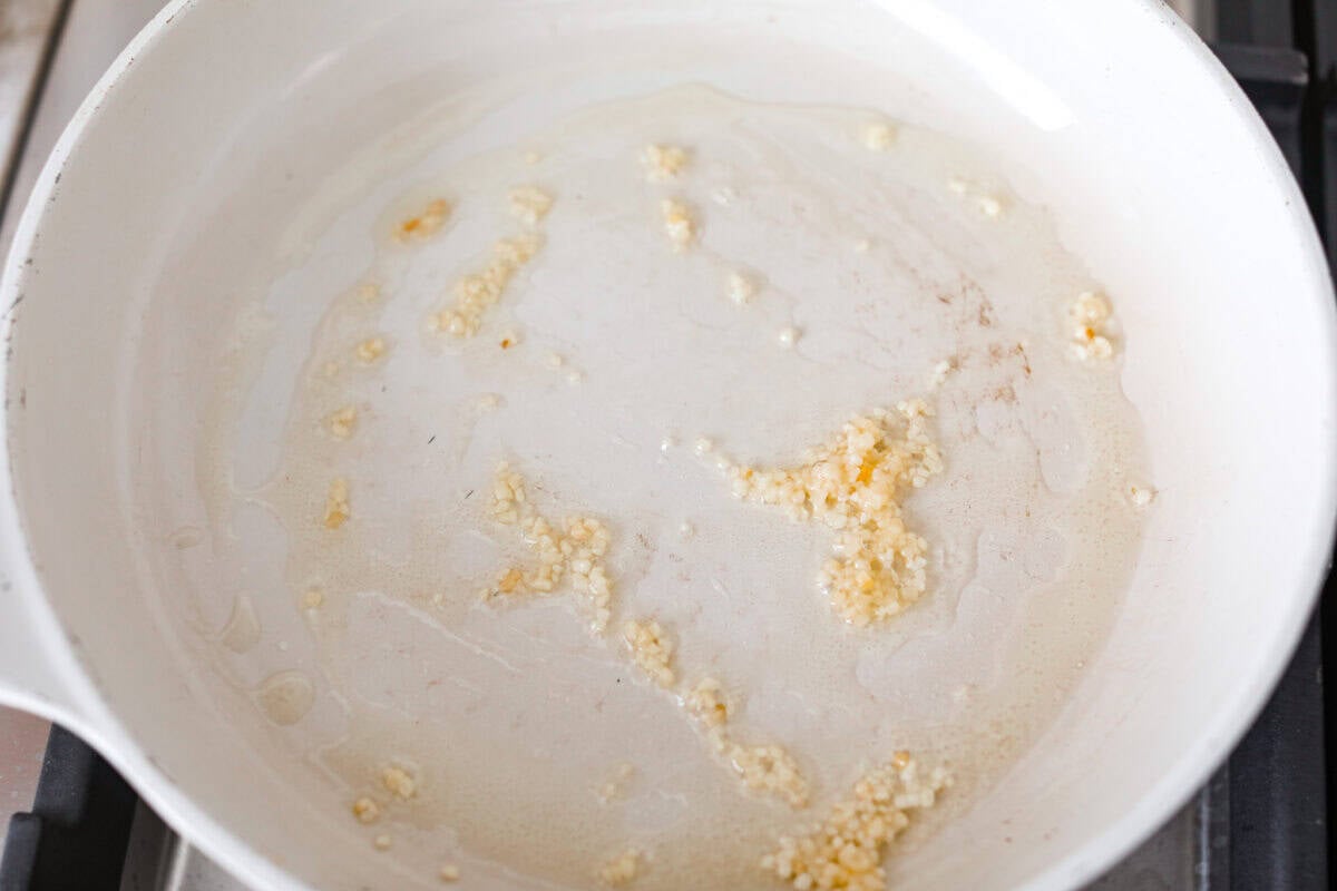 Garlic and olive oil cooking in a skillet.