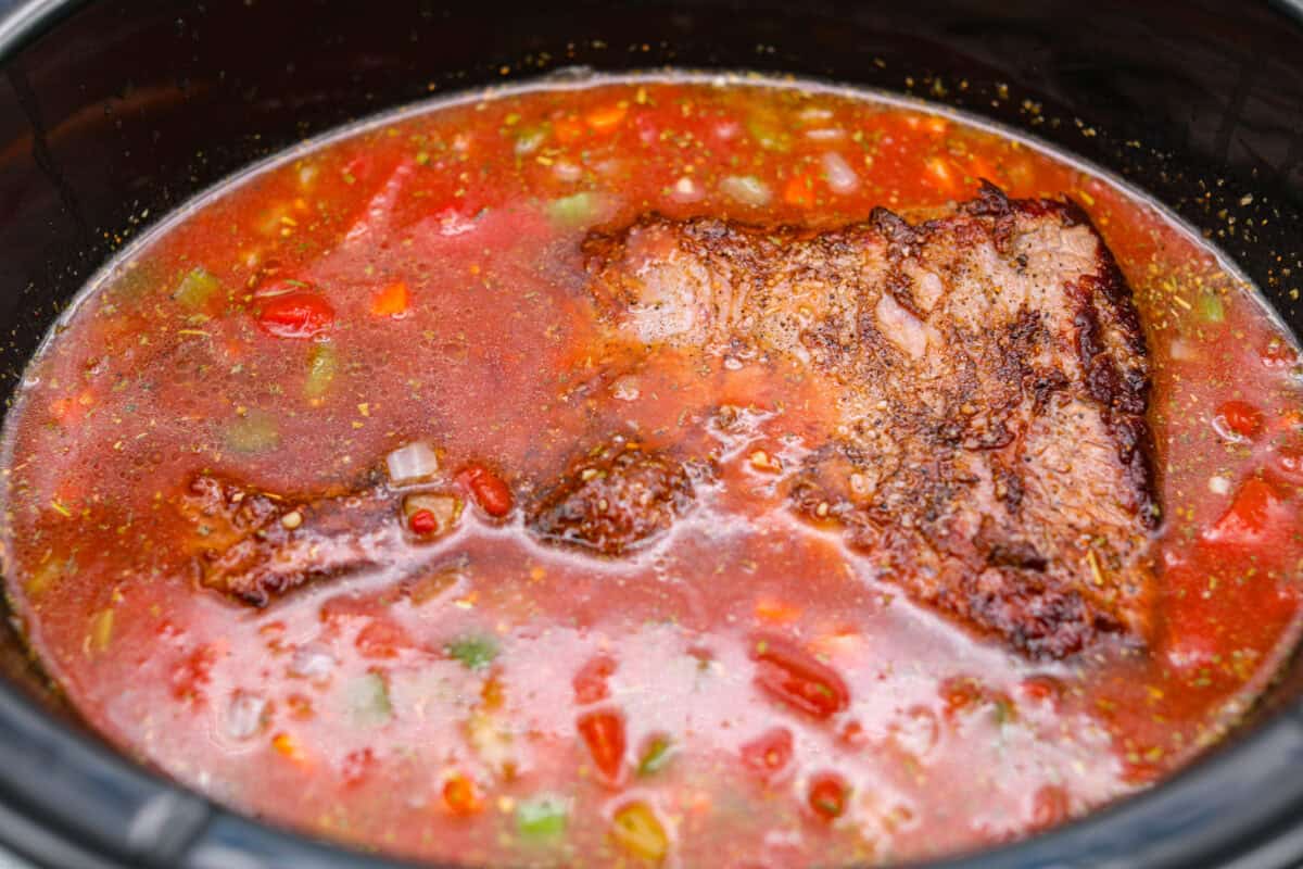 Brisket and sauce ingredients added to the slow cooker. 