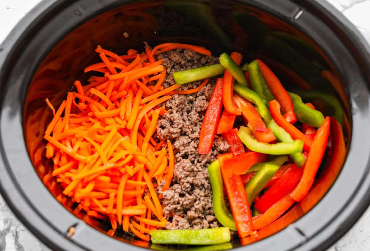 Slow cooker ramen gives you all the slurpy, saucy noodle bowl flavor with almost no effort. The veggies and beef slow cook in just an hour, then the ramen noodles go in for a quick 10 minutes. No hot oven, no boiling pots! Veggies and beef added to the crock pot.
