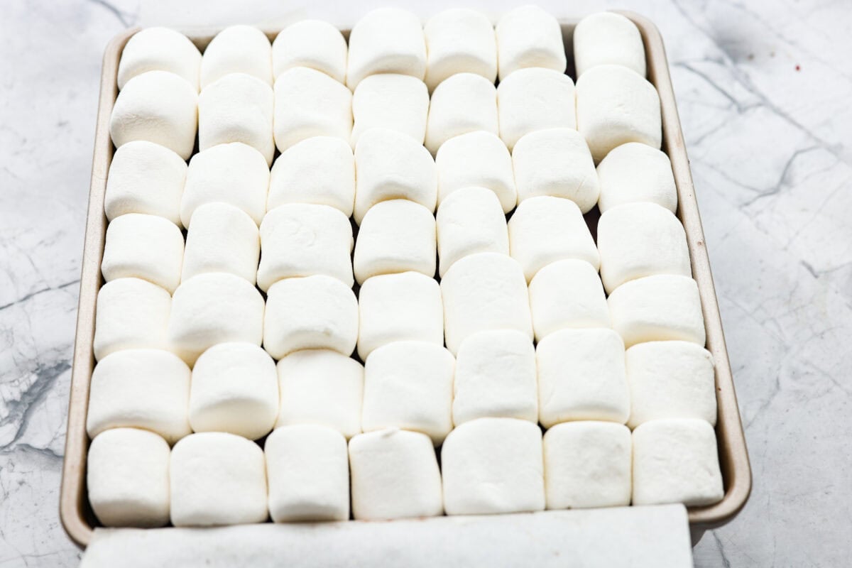 These s'mores brownies bring all the nostalgia of a campfire treat straight to your kitchen. Layers of buttery graham crackers, melty chocolate, fudgy brownie, and gooey marshmallows make every bite taste like summer. No fire pit required! Marshmallows spread on top of the brownie mixture.
