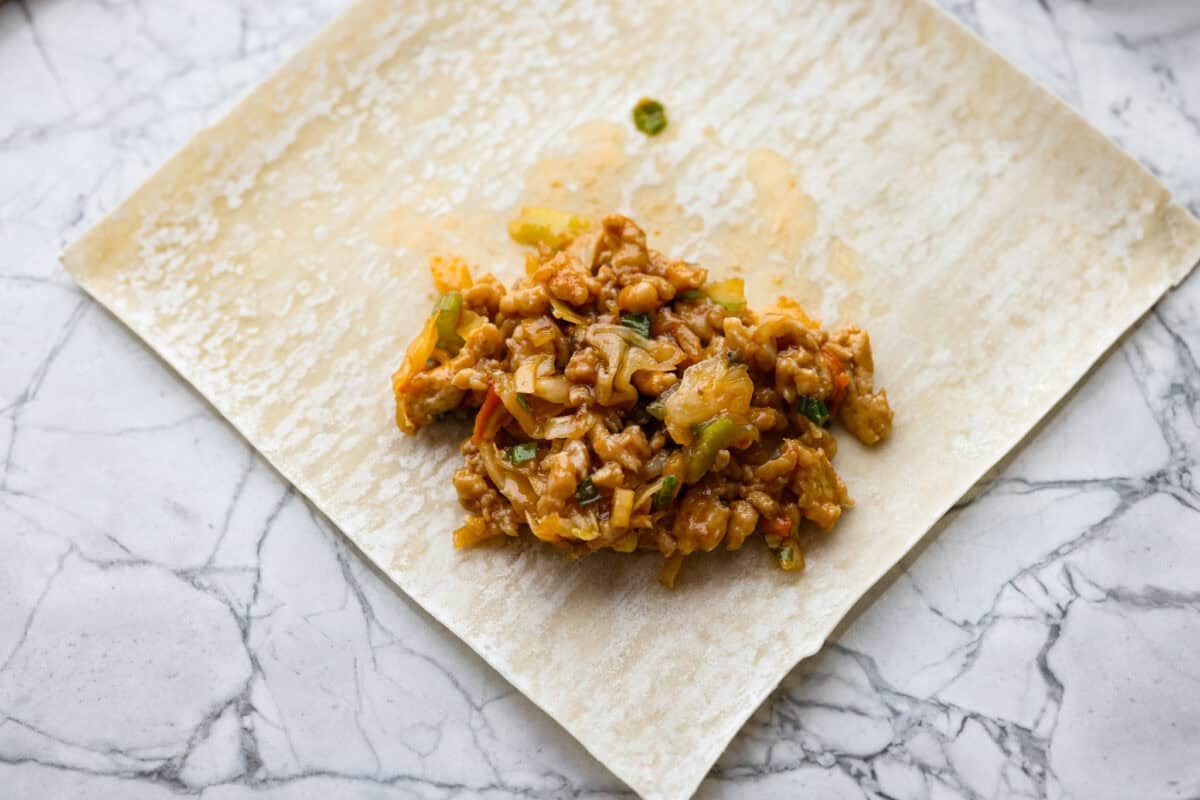 Small scoop of filing mixture added to an egg roll wrapper. 
