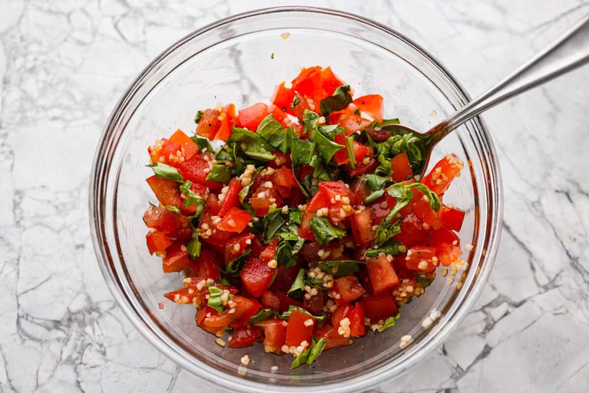 If you have fresh summer tomatoes sitting on your counter, this is your sign to make this Bruschetta Chicken Pasta. It's light, fresh, and shows that simple ingredients can make the best meals. Fresh bruschetta ingredients mixed together in a bowl.