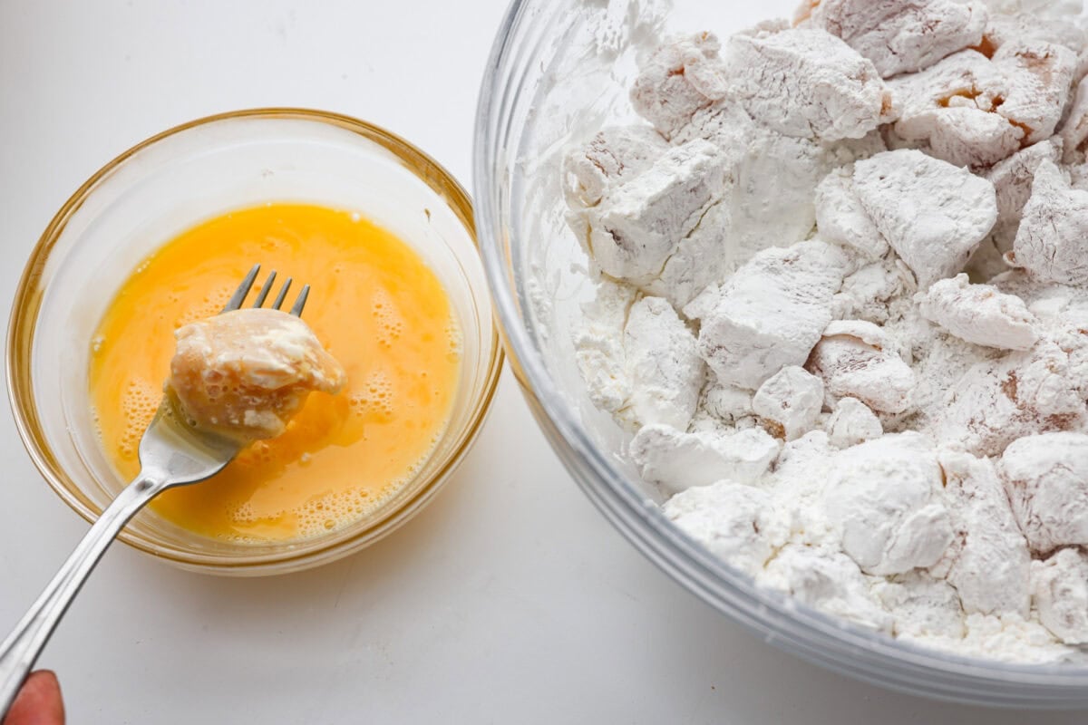 Bowl of egg next to a bowl of chicken coated in corn starch. 