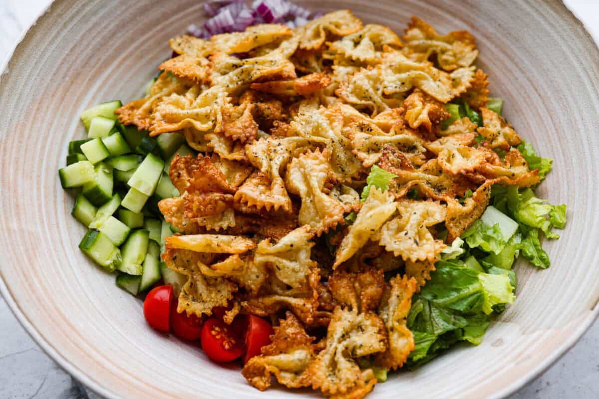 The viral crispy pasta salad trend is here, and it’s easy to see what the hype is about! Golden, crunchy pasta is tossed with fresh veggies and a creamy dressing for a fun upgrade that’s anything but boring. Salad ingredients added to a large serving bowl.