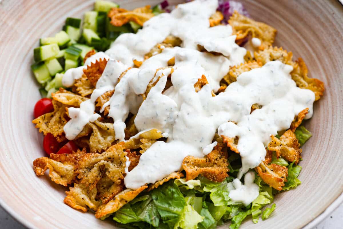 The viral crispy pasta salad trend is here, and it’s easy to see what the hype is about! Golden, crunchy pasta is tossed with fresh veggies and a creamy dressing for a fun upgrade that’s anything but boring. Dressing poured over the top of the salad ingredients.