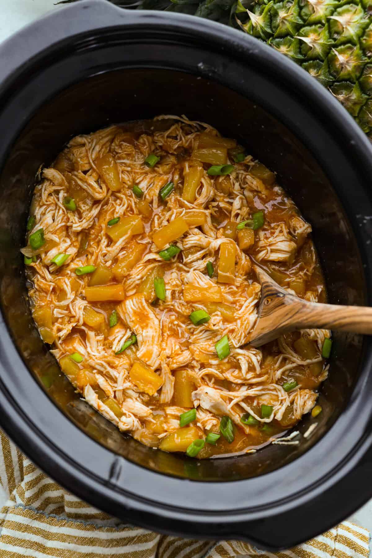 Slow cooker Aloha chicken is sweet, smoky, and so easy to throw together! Tender chicken cooks with pineapple, onion, and barbecue sauce until itβs full of flavor and ready to shred. Serve it over rice for a simple dinner the whole family will love. Crockpot full of tender slow cooker aloha chicken with pineapple and green onions.