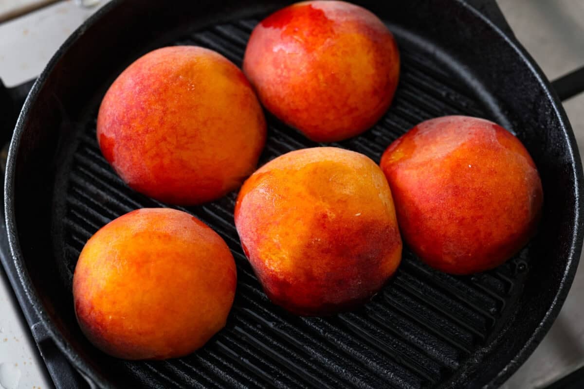 Peaches grilling on a grill pan.