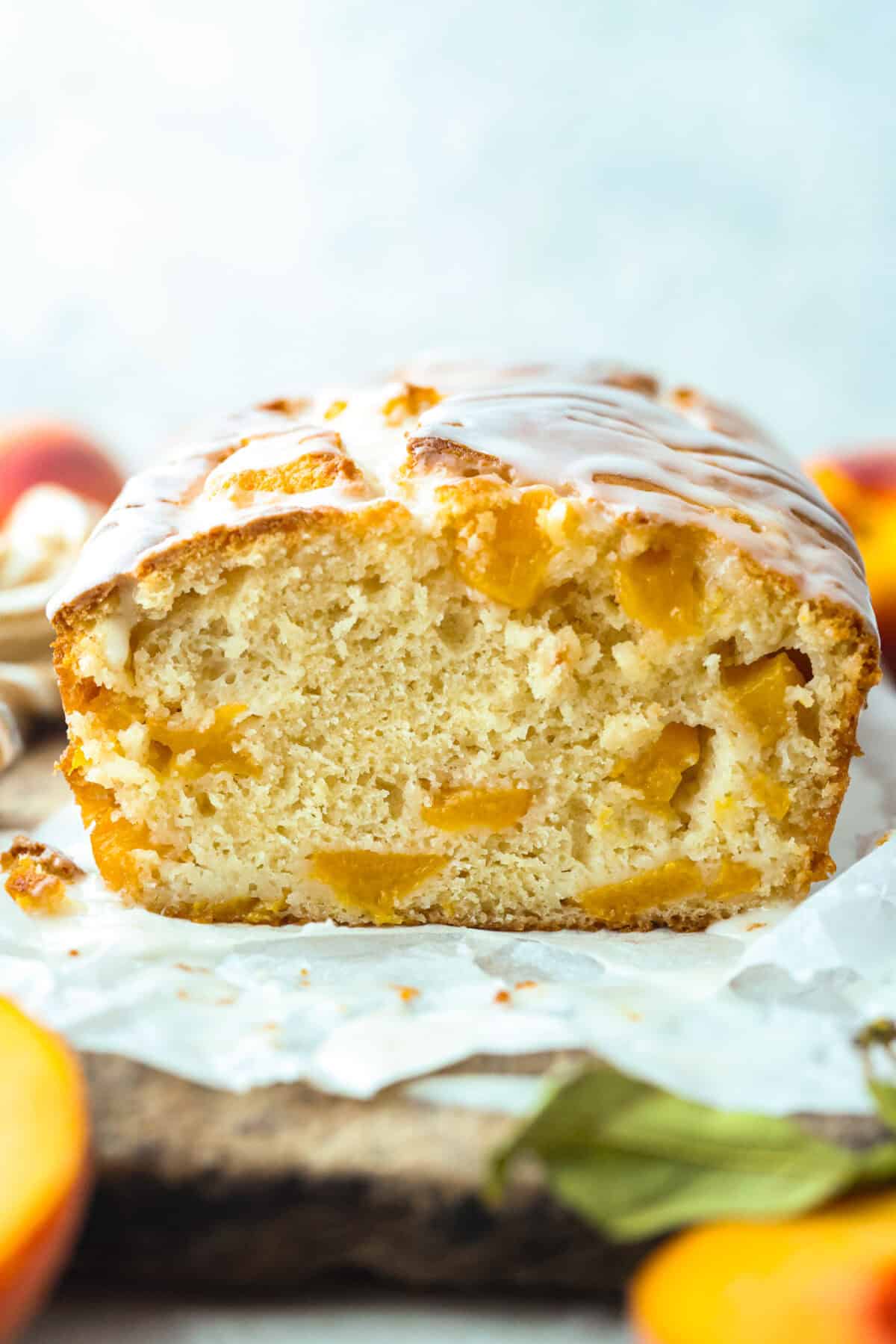 If you love peaches, this peach loaf belongs on your baking list! It’s incredibly moist, packed with sweet peaches, and topped with a peach glaze that makes every slice even more irresistible. Side shot of the peach loaf on a cutting board.
