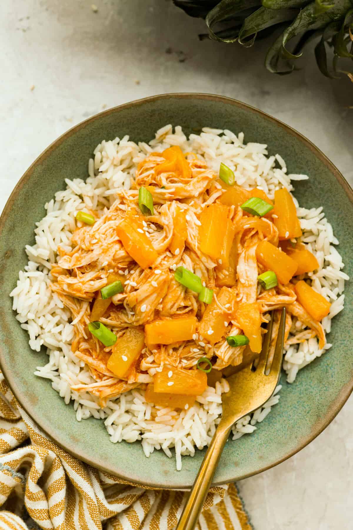 Slow cooker Aloha chicken is sweet, smoky, and so easy to throw together! Tender chicken cooks with pineapple, onion, and barbecue sauce until itβs full of flavor and ready to shred. Serve it over rice for a simple dinner the whole family will love. Plated slow cooker aloha chicken on a bed of rice.