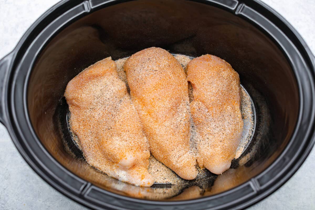 This crockpot chicken spaghetti will have everyone running to the dinner table! The slow cooker does the work while the chicken becomes tender and flavorful, then it's tossed with spaghetti, melty cheese, and a creamy sauce. Chicken breasts seasoned in. the bottom of the crockpot.