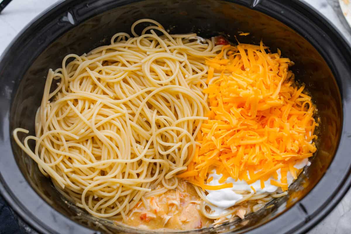 This crockpot chicken spaghetti will have everyone running to the dinner table! The slow cooker does the work while the chicken becomes tender and flavorful, then it's tossed with spaghetti, melty cheese, and a creamy sauce. Cooked spaghetti noodles, cheese and sour cream added to the chicken and sauce mixture.