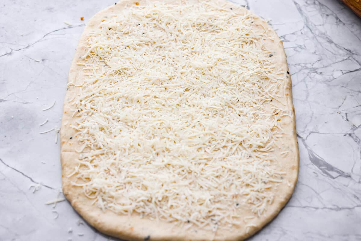 Everything bagel pull apart bread is soft, cheesy, and loaded with savory flavor in every layer. The homemade dough is stacked with Parmesan cheese and everything bagel seasoning, then baked until golden and fluffy. Dough rolled out into a rectangle and covered with parmesan cheese.
