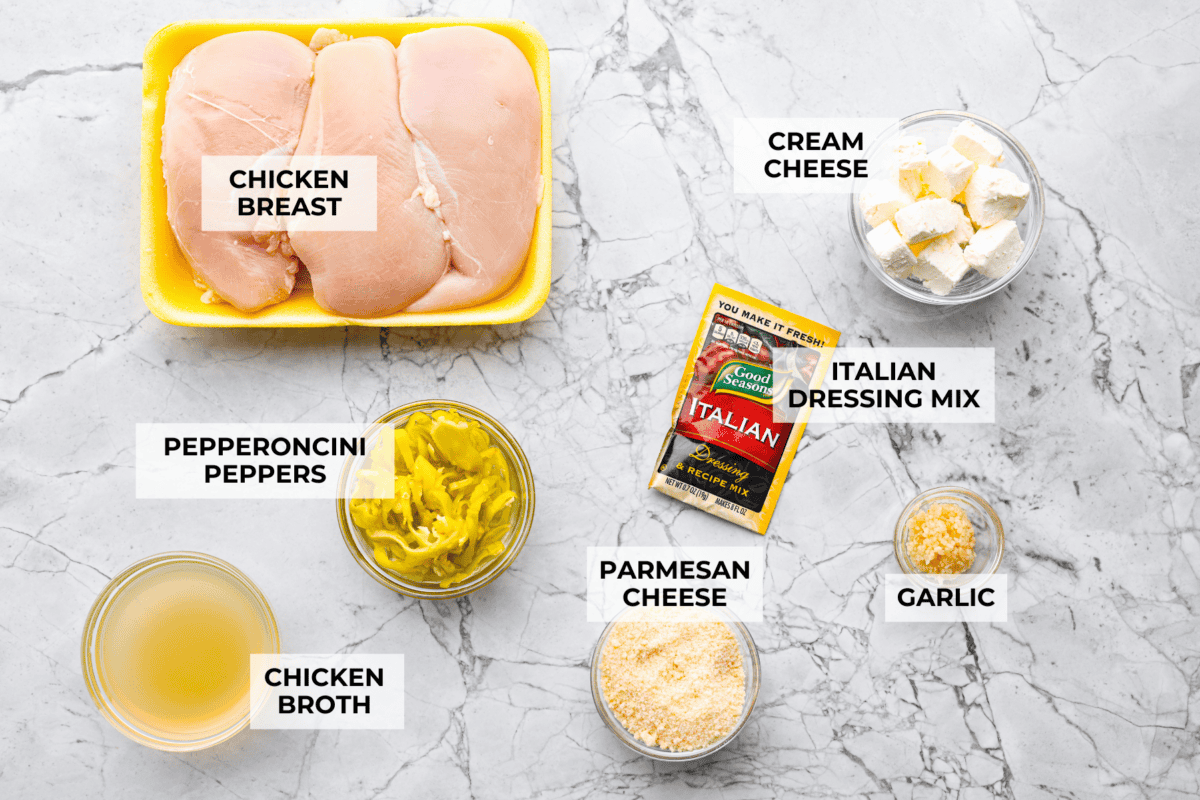 Crockpot Italian grinder chicken is an easy dinner packed with bold, tangy Italian flavor. Tender shredded chicken turns creamy and delicious in the slow cooker. Serve it on toasted hoagie rolls or over pasta for a simple family dinner. Overhead shot of labeled ingredients.