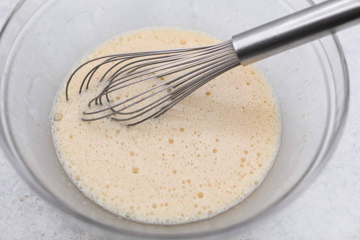 This invisible apple cake is a little magical! Paper-thin apple slices are coated in a simple, lightly spiced batter, then layered in a loaf pan and baked into a tender, custardy cake. Such a delicious way to enjoy fresh apples! Wet ingredients whisked together in a mixing bowl.