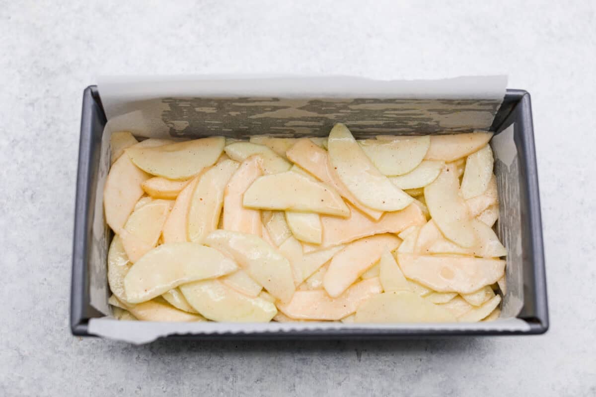 This invisible apple cake is a little magical! Paper-thin apple slices are coated in a simple, lightly spiced batter, then layered in a loaf pan and baked into a tender, custardy cake. Such a delicious way to enjoy fresh apples! Apple and batter mixture added to the loaf pan.
