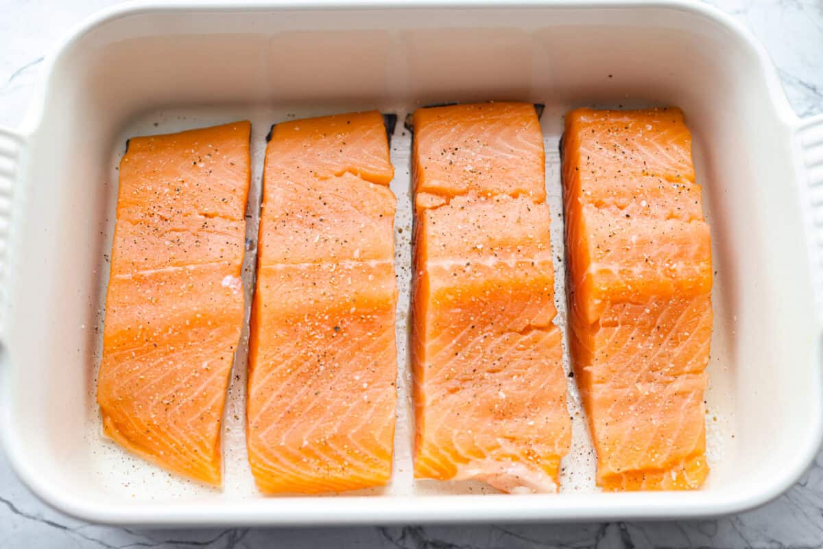 Maple glazed salmon has that perfect sweet-and-savory flavor that keeps you going back for just one more bite. As it bakes, the maple glaze turns glossy and caramelized while the salmon stays buttery, flaky, and melt-in-your-mouth tender. Seasoned salmon filets in a baking dish.