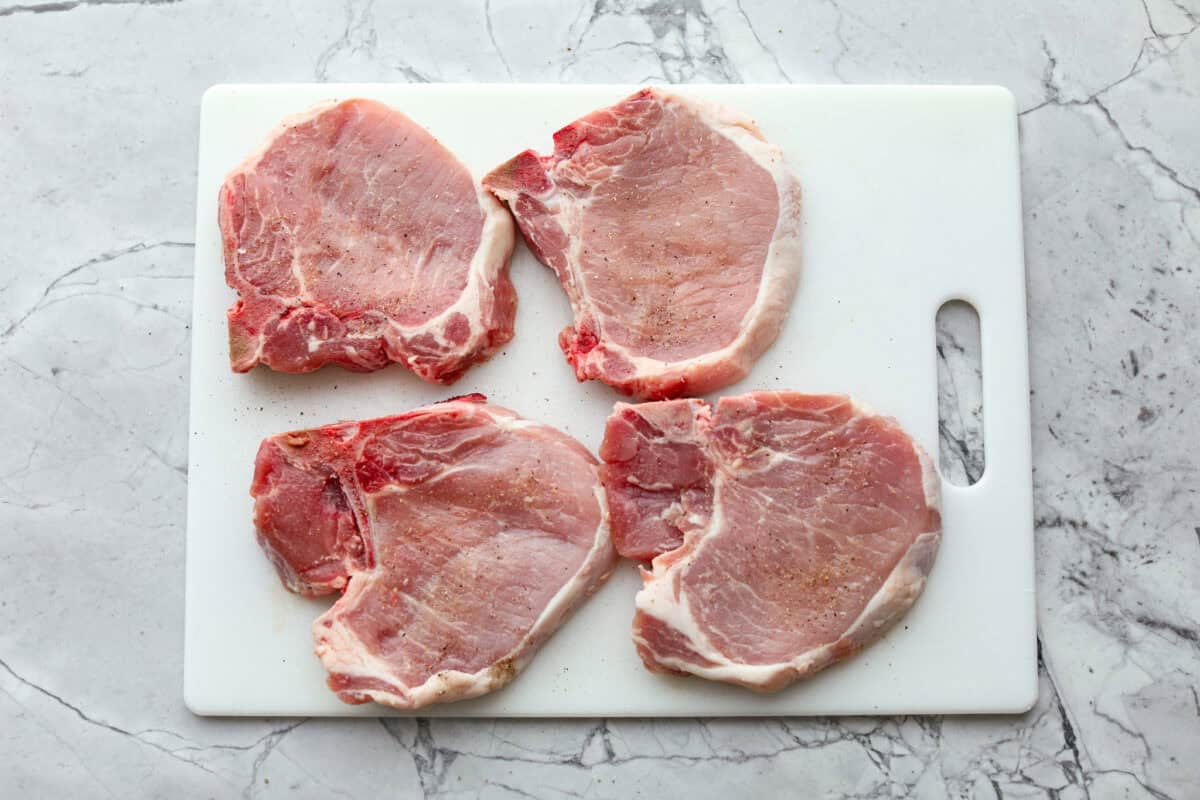 Pork chops seasoned on a cutting board. 