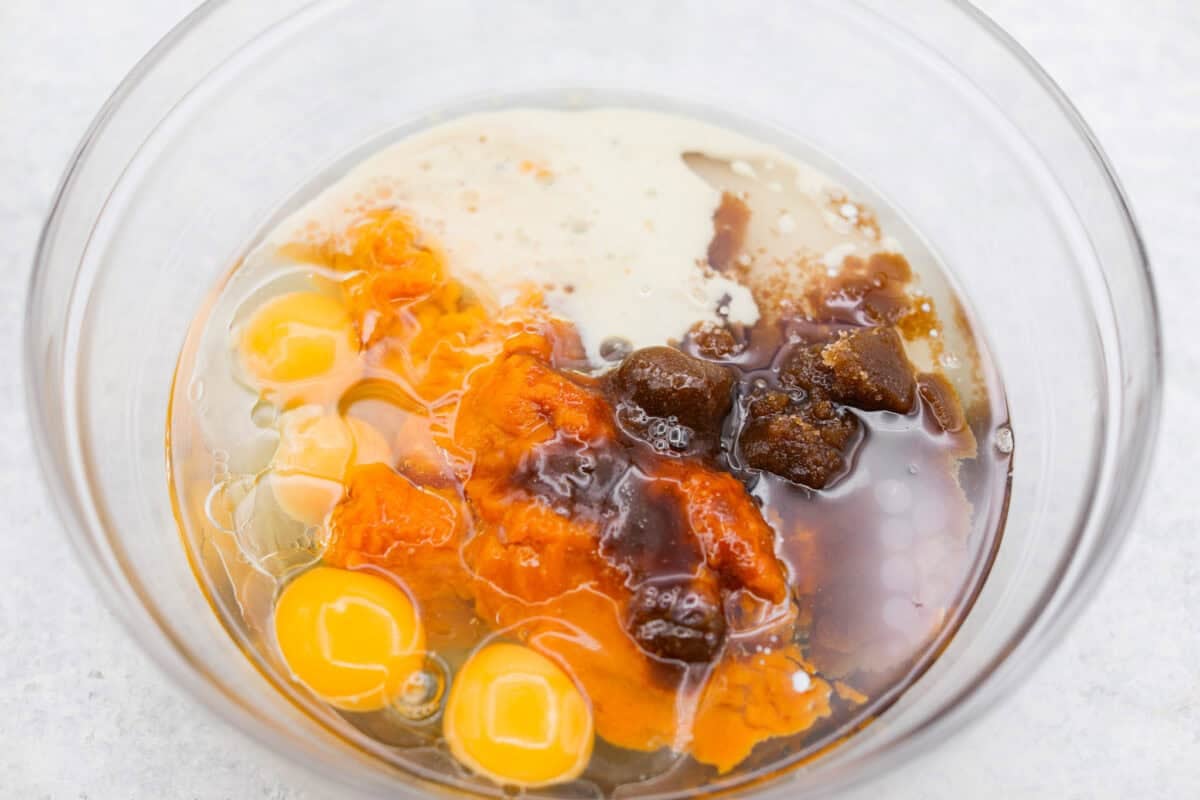 Wet pumpkin sheet cake ingredients added to a mixing bowl. 