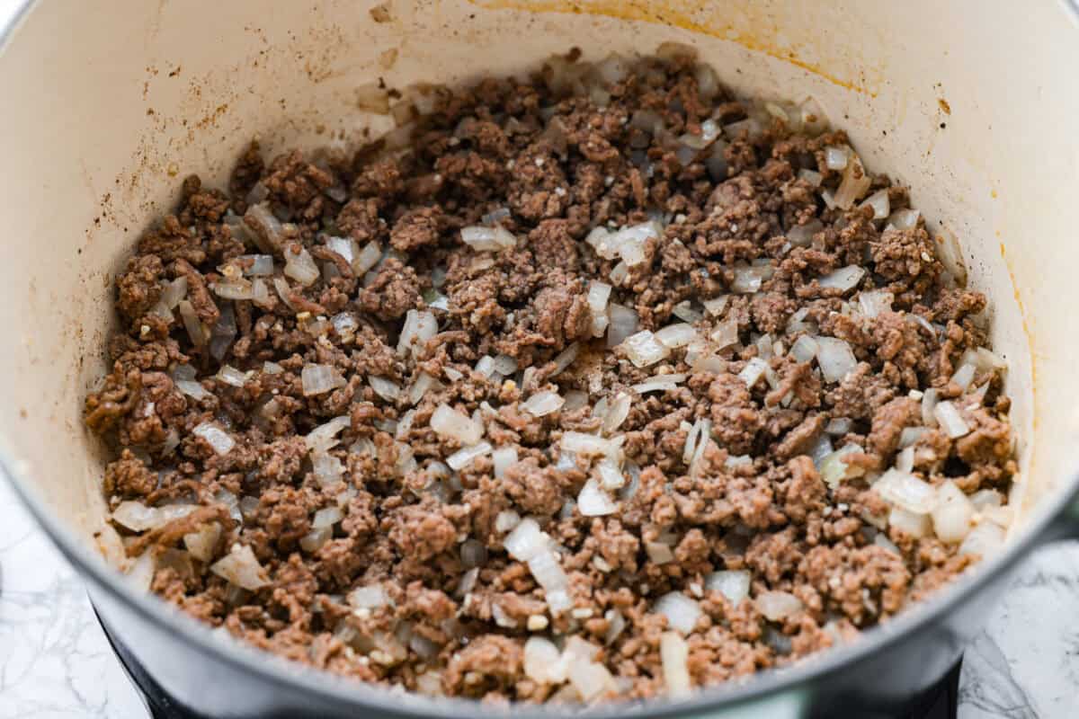 Shepherd’s pie soup has all the cozy, comforting flavors of classic shepherd’s pie in one hearty bowl! Think savory beef, tender potatoes, vegetables, and melted cheddar in a rich, creamy broth. It’s classic comfort food with a fun twist! Ground beef and onions cooking in a pot.