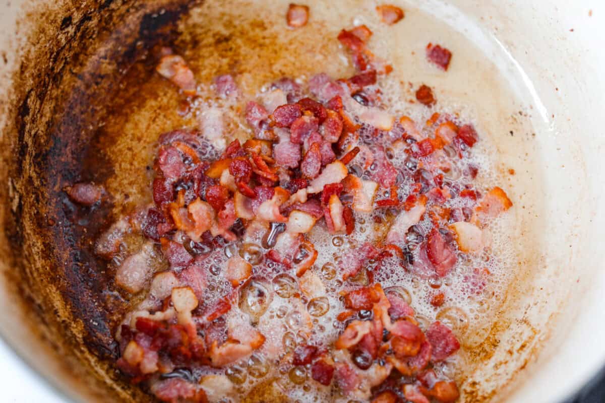 No tomatoes, no red sauce, just a rich, savory white bolognese loaded with beef, pork, bacon, white wine, and plenty of Parmesan. Tossed with noodles, it’s a fun and seriously delicious twist on classic Bolognese. Bacon cooking in a pot.