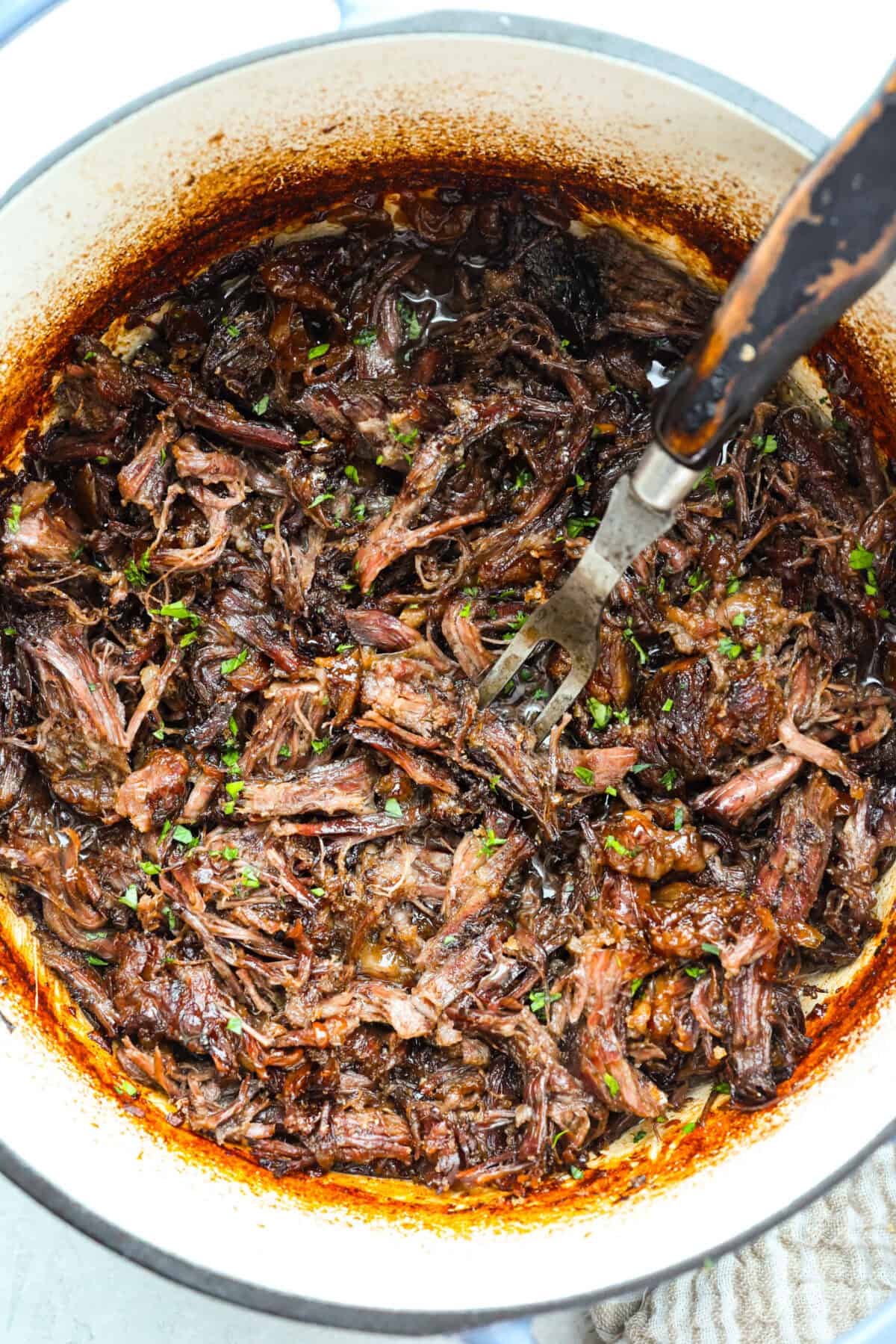 Caramelized chuck roast is everything I want in a cozy dinner. The beef cooks low and slow until it practically falls apart, then gets sprinkled with brown sugar and broiled until the edges are sticky, caramelized, and SO good. Overhead shot of caramelized chuck roast shredded and crispy from being broiled.