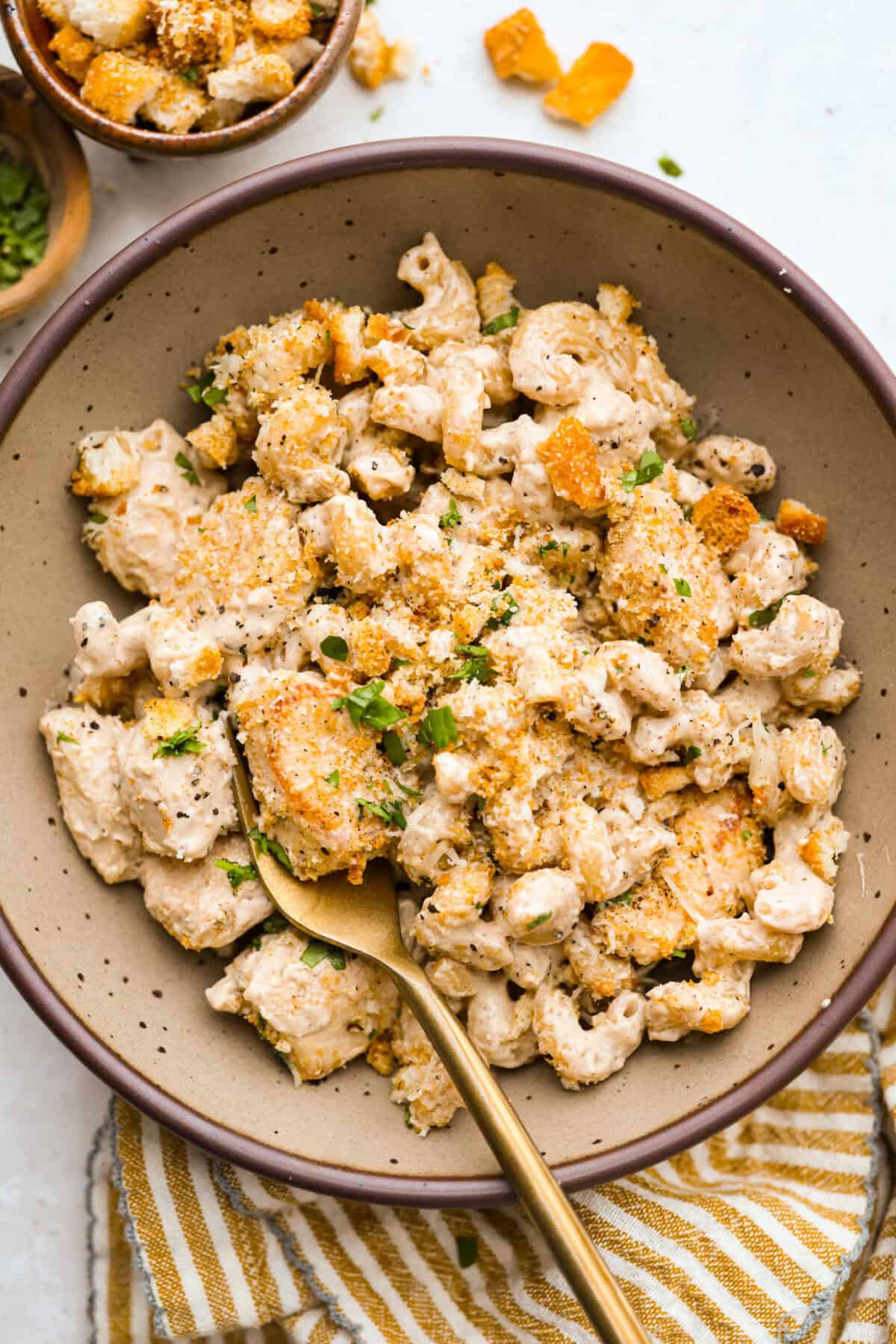 Serving of chicken Caesar pasta in a bowl with a gold spoon. 