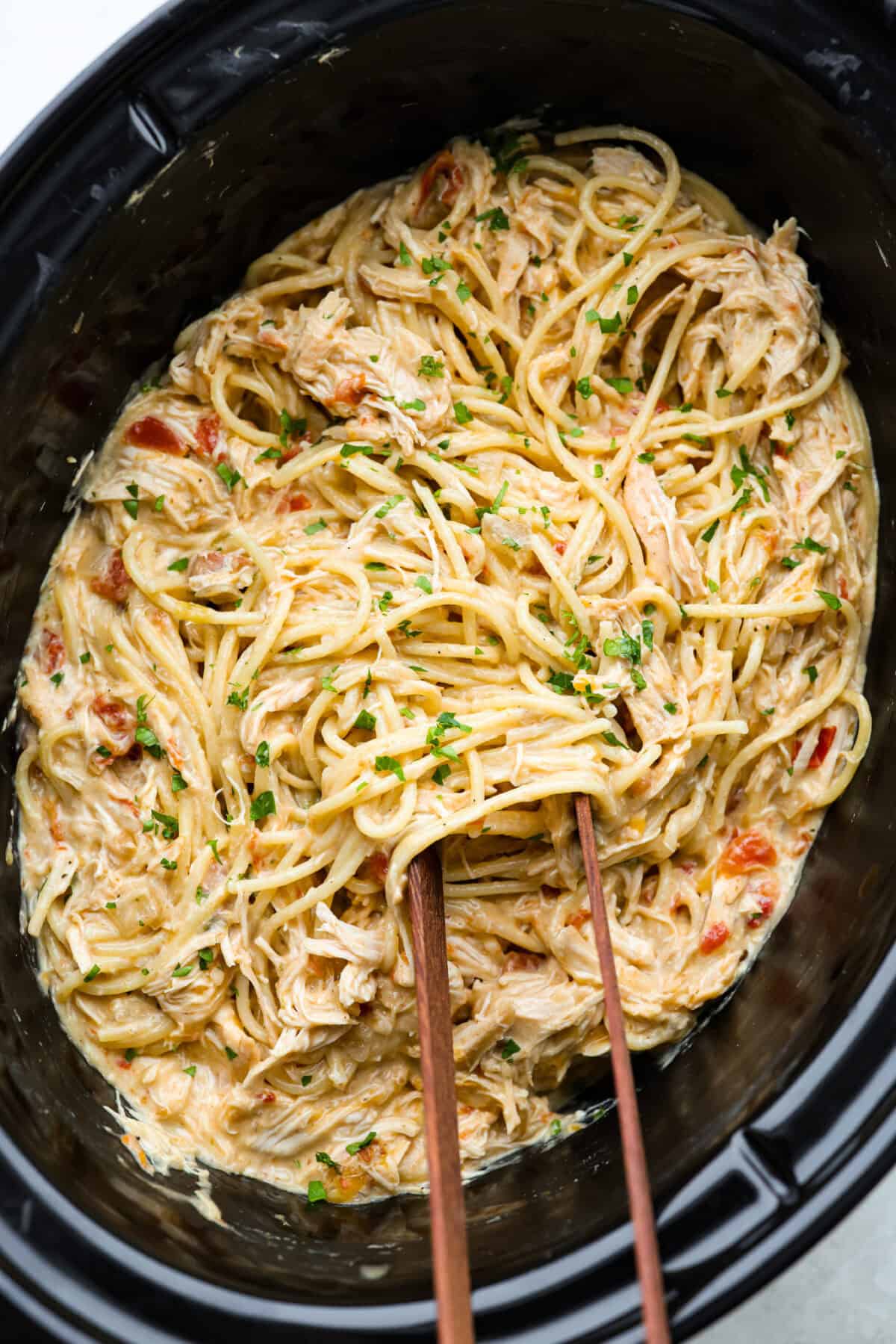 This crockpot chicken spaghetti will have everyone running to the dinner table! The slow cooker does the work while the chicken becomes tender and flavorful, then it's tossed with spaghetti, melty cheese, and a creamy sauce. Overhead shot of crockpot chicken spaghetti.