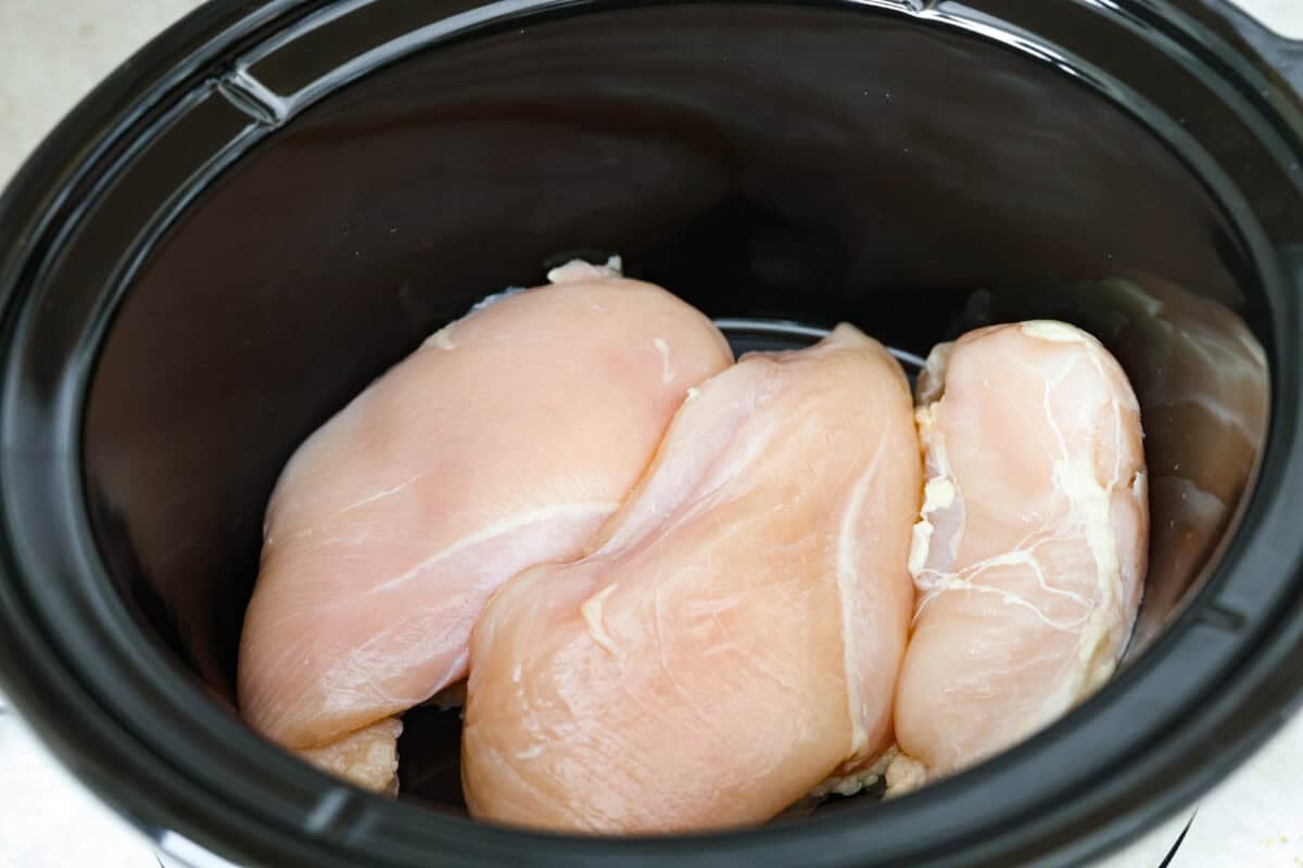 Crockpot creamy chicken pasta is the kind of dinner I need on a busy weeknight! Tender chicken cooks all day in a creamy marinara sauce, then you stir in pasta and cheese for the easiest comfort food dinner. Chicken breasts added to the bottom of the crockpot.