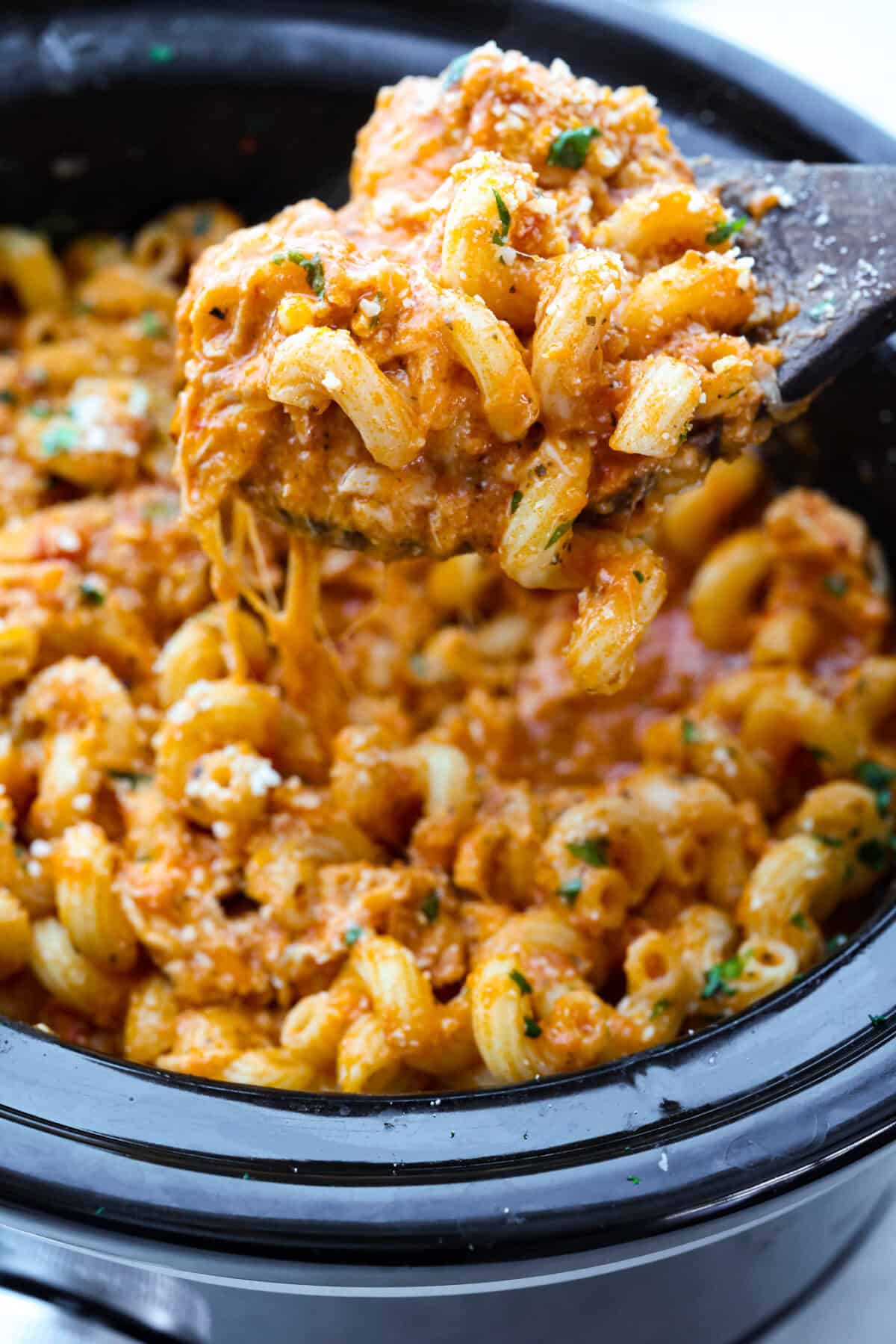 Crockpot creamy chicken pasta is the kind of dinner I need on a busy weeknight! Tender chicken cooks all day in a creamy marinara sauce, then you stir in pasta and cheese for the easiest comfort food dinner. Close up shot of a scoop of crockpot creamy chicken pasta.