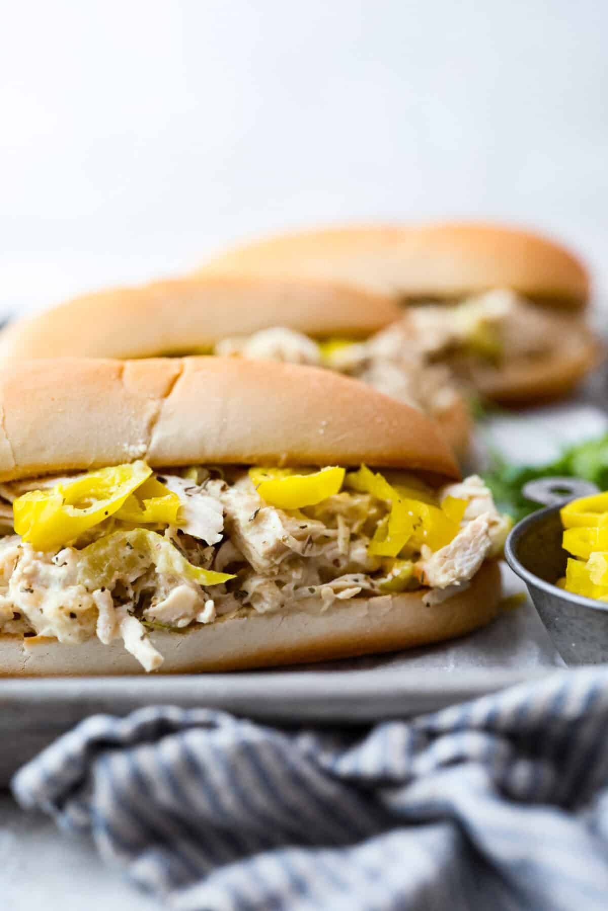 Crockpot Italian grinder chicken is an easy dinner packed with bold, tangy Italian flavor. Tender shredded chicken turns creamy and delicious in the slow cooker. Serve it on toasted hoagie rolls or over pasta for a simple family dinner. Crockpot Italian grinder chicken added to a hoagie bun.