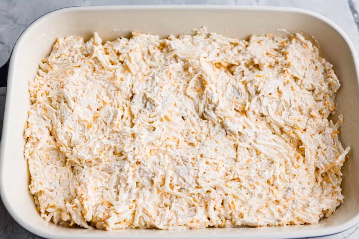 Fully combined casserole ingredients mixed together and spread around the bottom of a baking dish. 